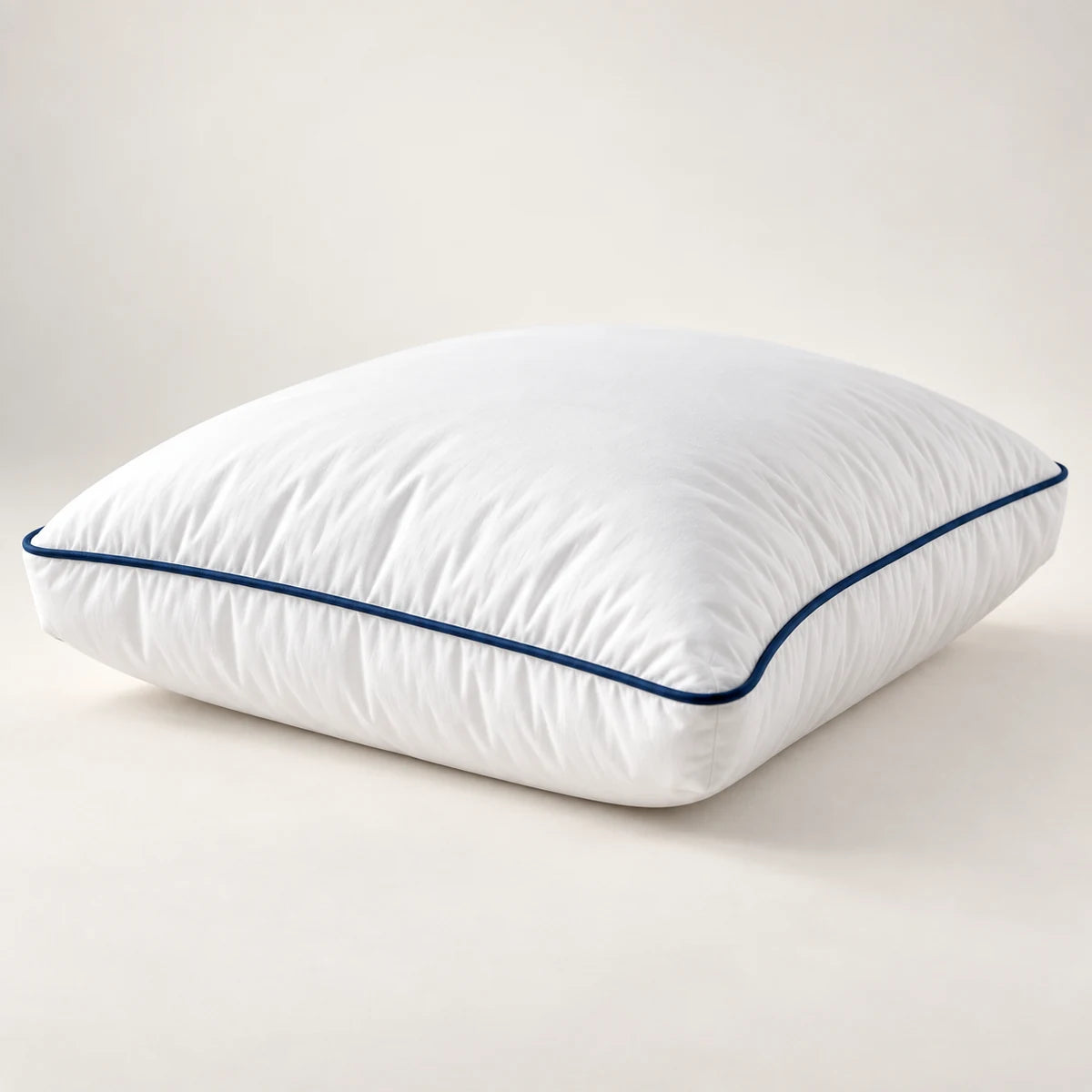 Close view of a white gusseted pillow with navy piping and plush loft
