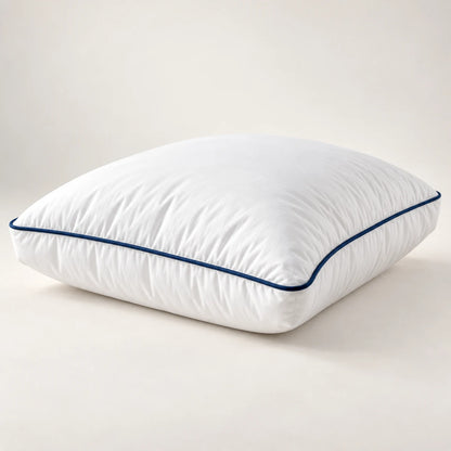 Close view of a white gusseted pillow with navy piping and plush loft
